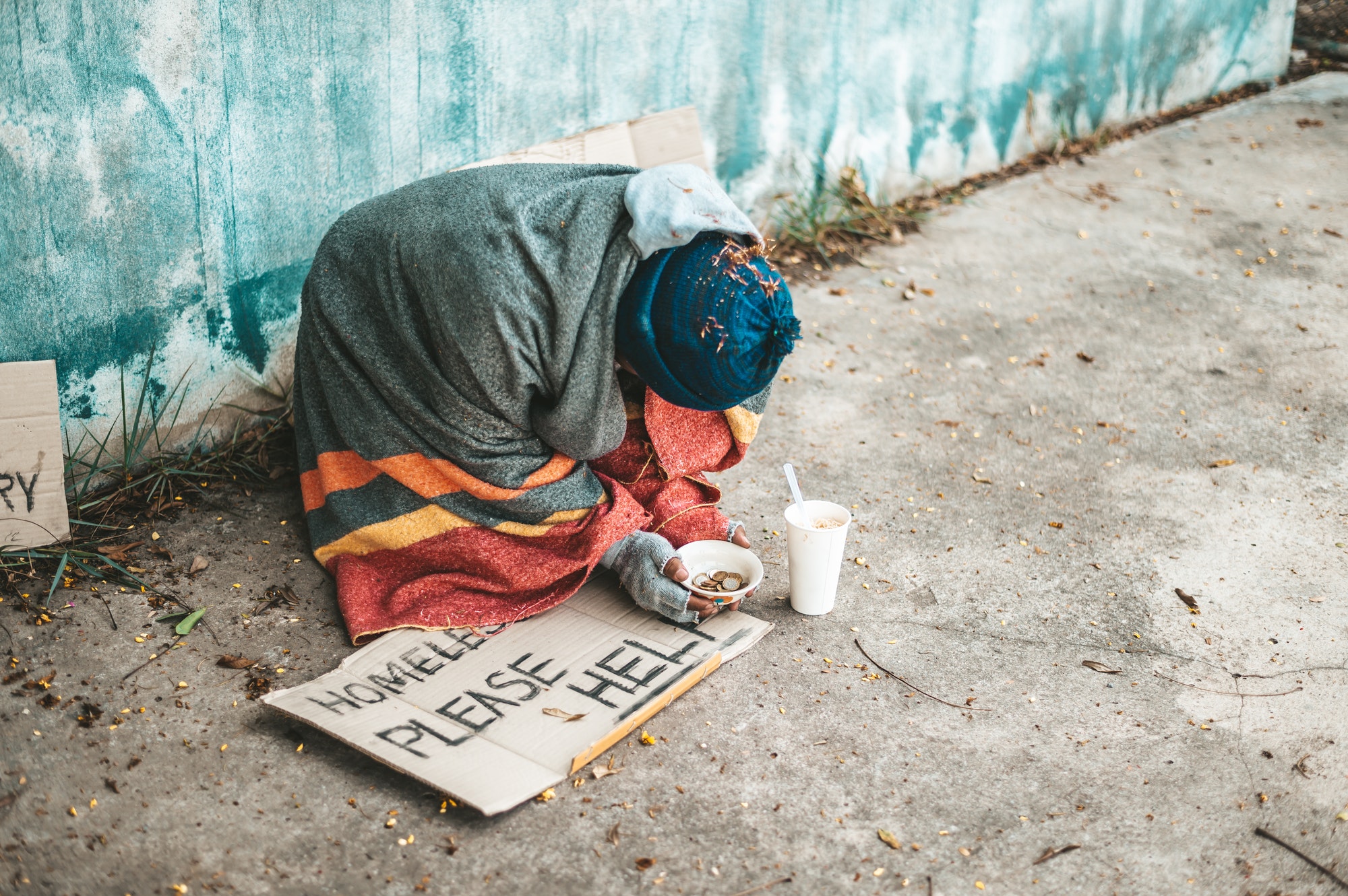 beggars sitting on the street with homeless messages please help